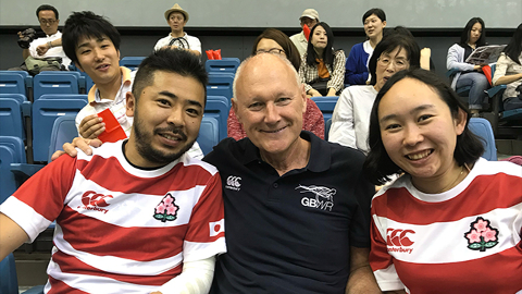 David Pond sits with two Japanese attendees at the Paralympic games.